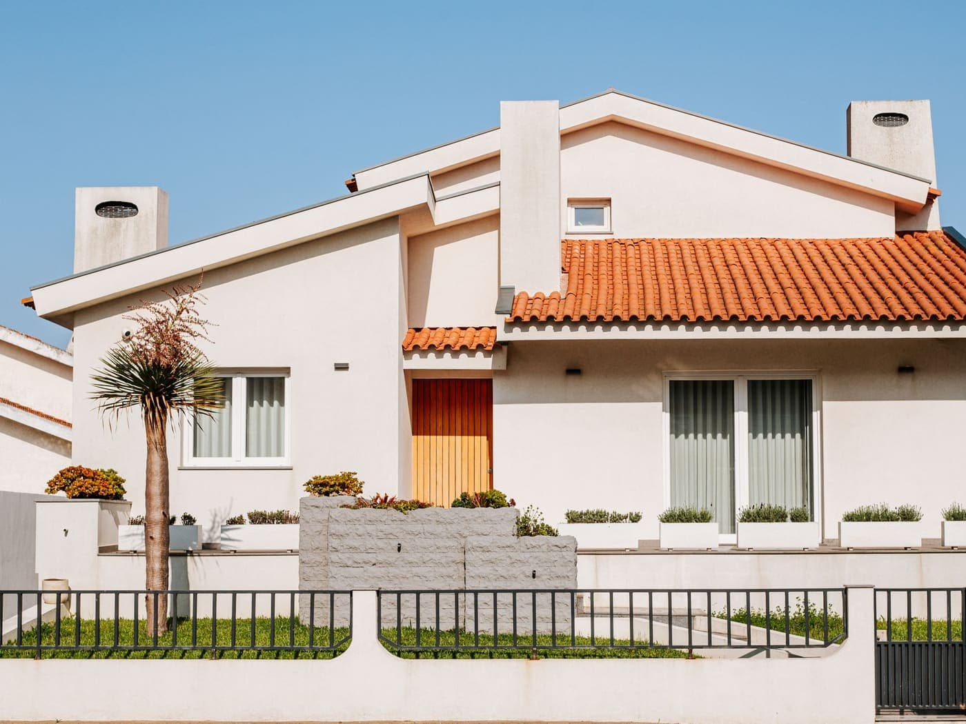 Maison aux tuiles orangées et palmier sous un ciel bleu